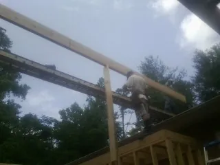 Carpenter setting a ridge beam over a new addition frame — Ice Dam Removal by Roofing Brothers in Malin