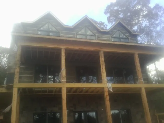 Dormers and porch framing on a large log home under construction — Roof Coating work by our crew in Malin