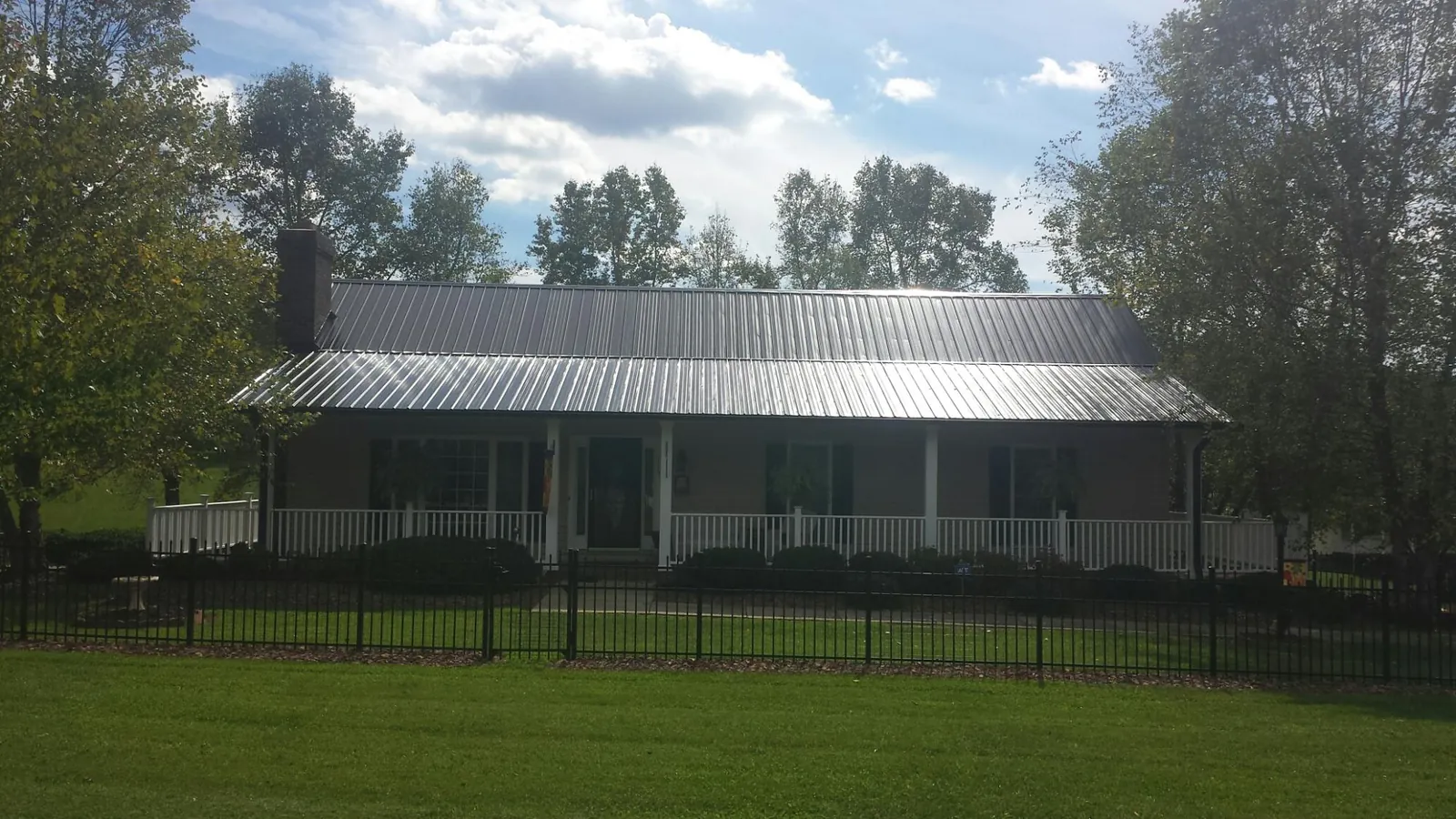 Gray metal roof on a brick ranch with a full width front porch — Gutter Guard Installation work by our crew in Malin