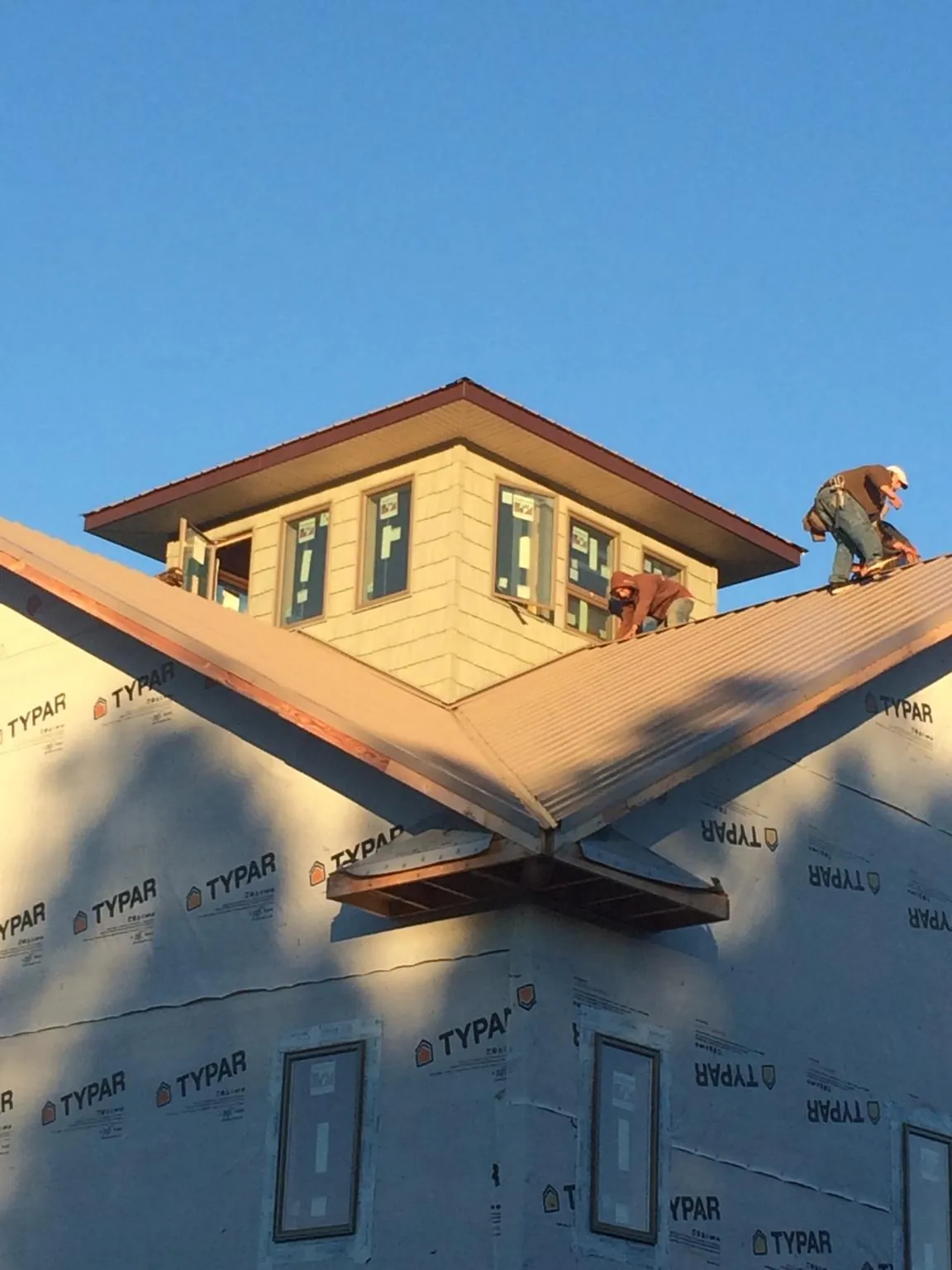 Roofers working around a rooftop cupola on a new metal roof at sunset — Roof Waterproofing in Malin by Roofing Brothers